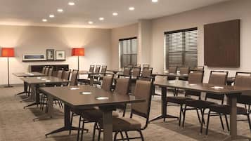 A conference room with multiple tables and chairs, equipped with overhead lighting and framed pictures on the walls.