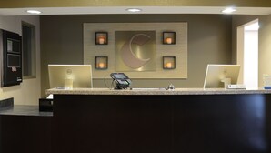 A reception desk with a large logo, a digital kiosk, and a computer monitor.