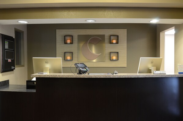 A reception desk with a large logo, a digital kiosk, and a computer monitor. - Comfort Inn & Suites Cave City (Cave City)
