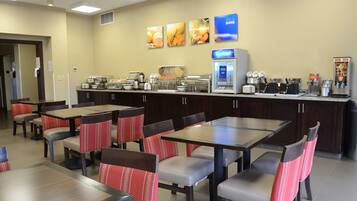 A restaurant with multiple tables and chairs, a coffee machine, and a refrigerated display case.
