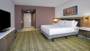 Una habitación de hotel con una cama, televisión, escritorio y un cuadro en la pared.
