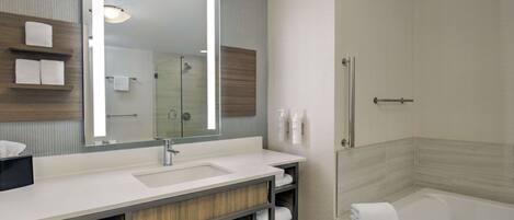 A modern bathroom with a large mirror, a sink, a bathtub, and shelves with towels.