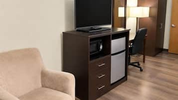 Una habitación de hotel con cama, escritorio con computadora, silla, televisor y armario.