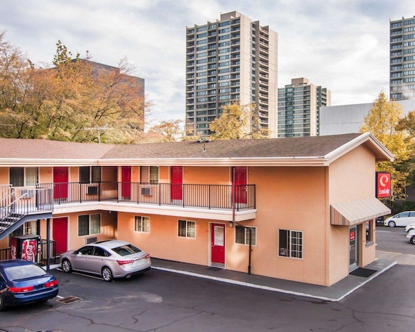 Un motel con una estructura de dos pisos, un estacionamiento y una máquina expendedora de Coca-Cola.