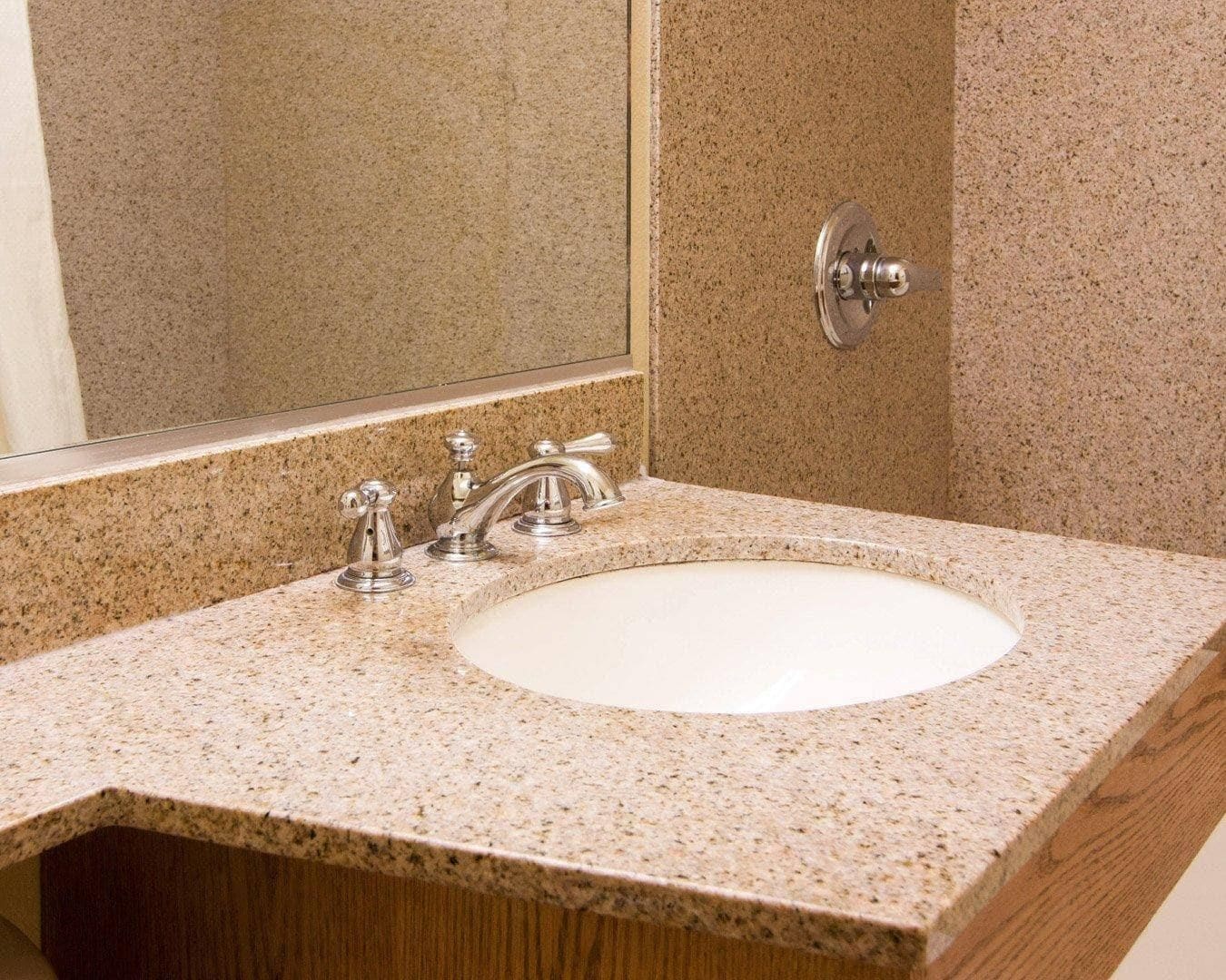 A bathroom with a granite countertop, a white sink, and a mirror.