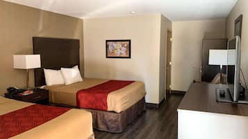 A hotel room with two beds, a desk, a chair, a TV, and a framed picture on the wall.