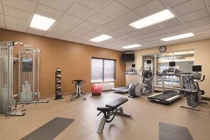 A gym with various exercise equipment, including a treadmill, elliptical, and weight machines.