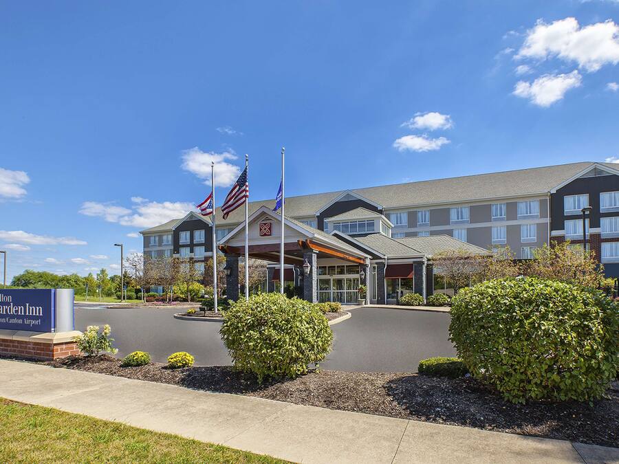 Ett Hilton Garden Inn med en modern byggnad, en överbyggd entré och amerikanska flaggor.