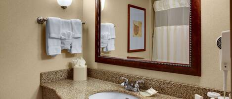 A bathroom with a granite countertop sink, a large mirror, and two wall-mounted towel racks.