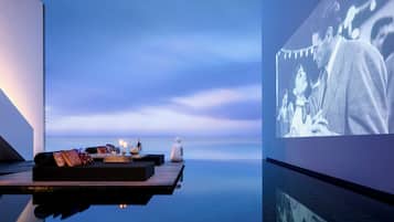 A serene outdoor seating area with a table set for two, overlooking a calm body of water.