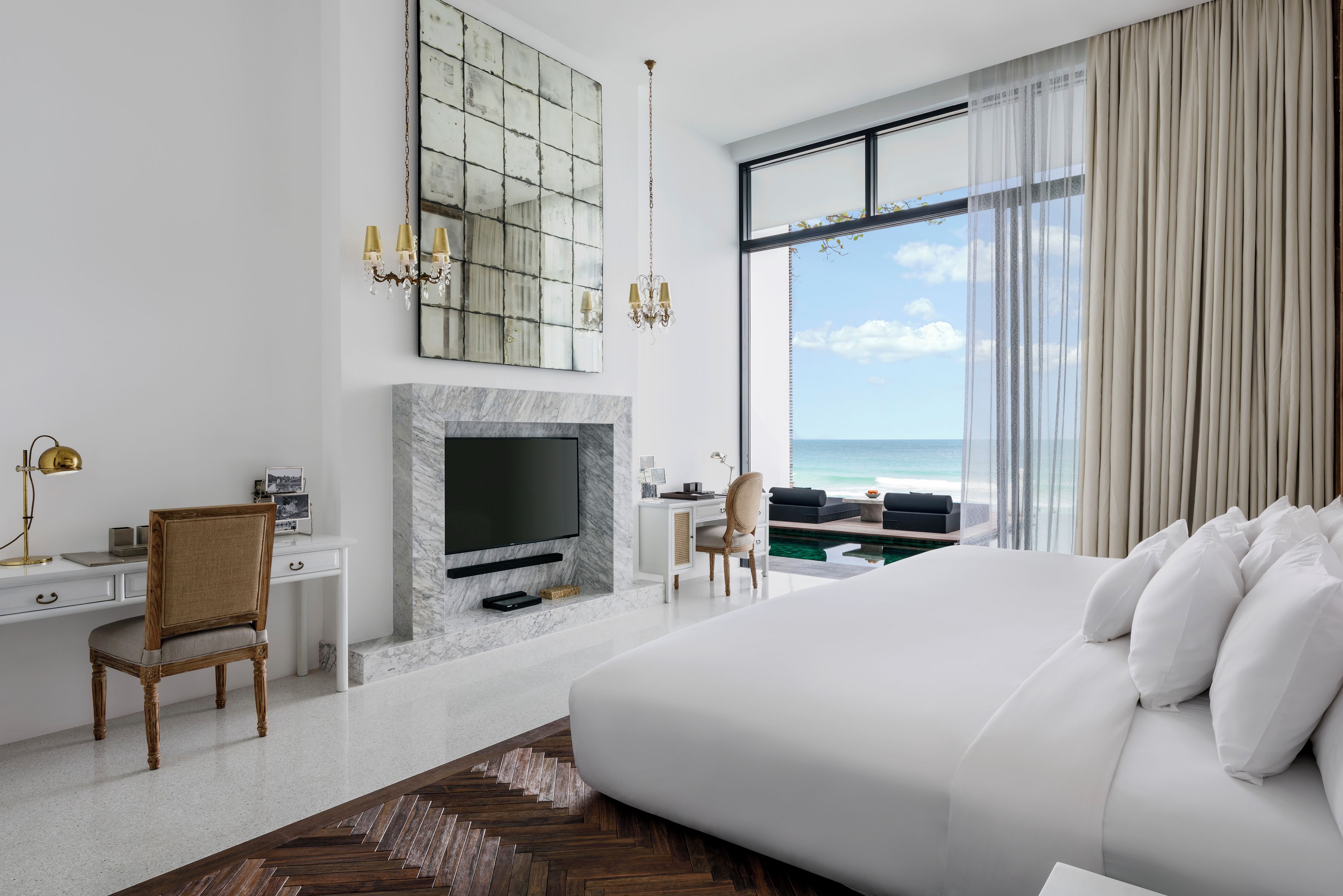 Une chambre d’hôtel moderne dotée d’un grand lit, d’une télévision, d’un bureau et offrant une vue sur l’océan.