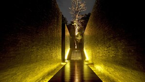 A narrow, brick-walled corridor with a wooden floor and a tree in the center. - The Library (Koh Samui)