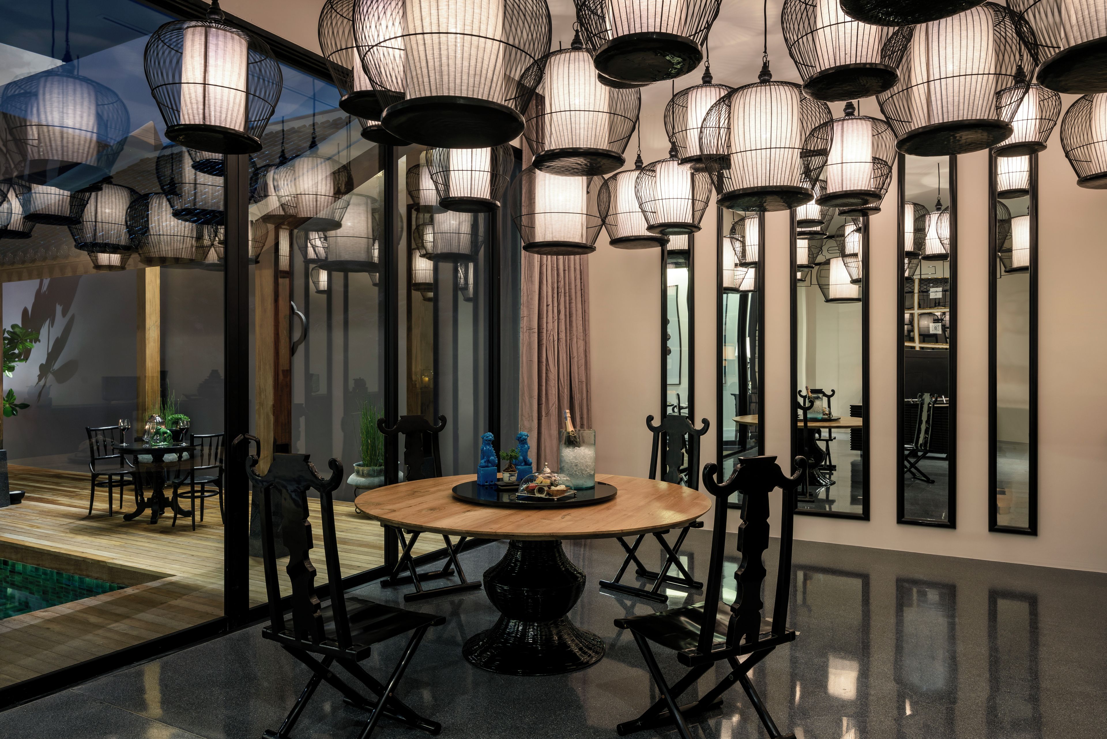 A modern dining area with a round table, black chairs, and hanging light fixtures.