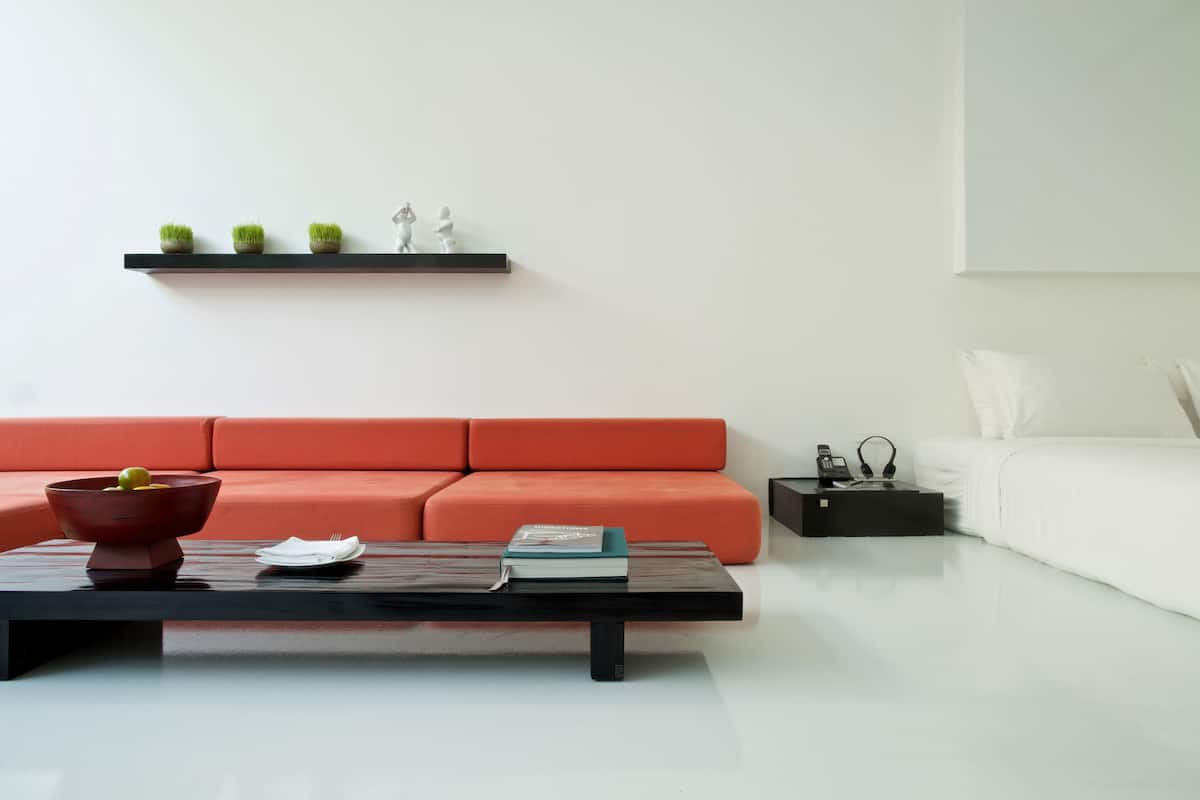 A modern living room with a black coffee table, a red sofa, a white sofa, and a black side table with a lamp.