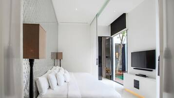 A modern bedroom with a large bed, a flat-screen TV mounted on the wall, and a view of the outdoors through a glass door.