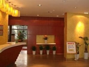 A reception area with a curved reception desk, potted plants, a wall-mounted sign, and a window in the background. - Jinjiang Inn ChengDu Wenshufang (Chengdu)