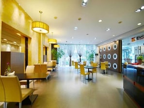 A modern hotel lobby with yellow chairs, tables, and a large wall with circular patterns. - Jinjiang Inn ChengDu Wenshufang (Chengdu)