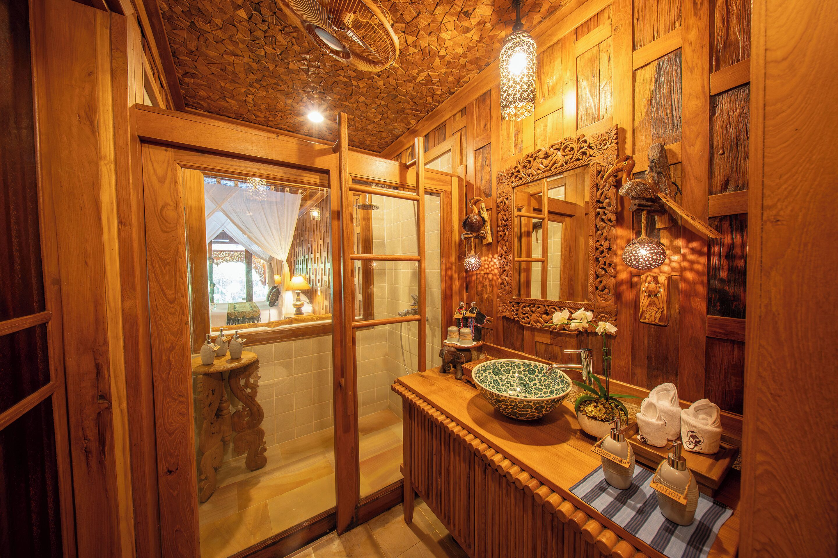 A wooden bathroom with a large mirror, a wooden sink, and a shower area.