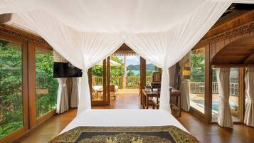 A room with a large bed, a TV, and a view of a balcony with outdoor furniture.