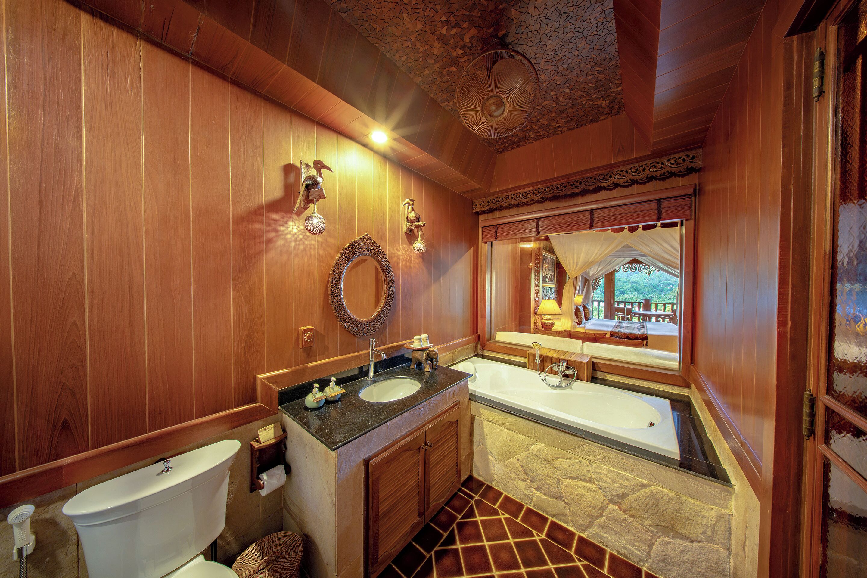 A wooden bathroom with a toilet, sink, and bathtub.