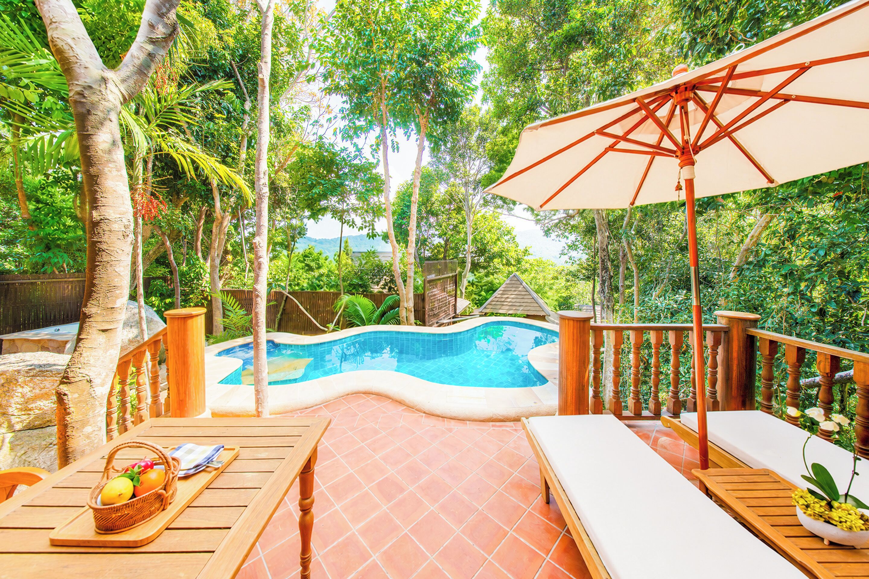 Ein Poolbereich mit Holzterrasse, Liegestühlen und Sonnenschirm.