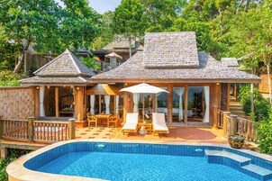 Una casa de madera tradicional con piscina, mobiliario exterior y un porche cubierto.