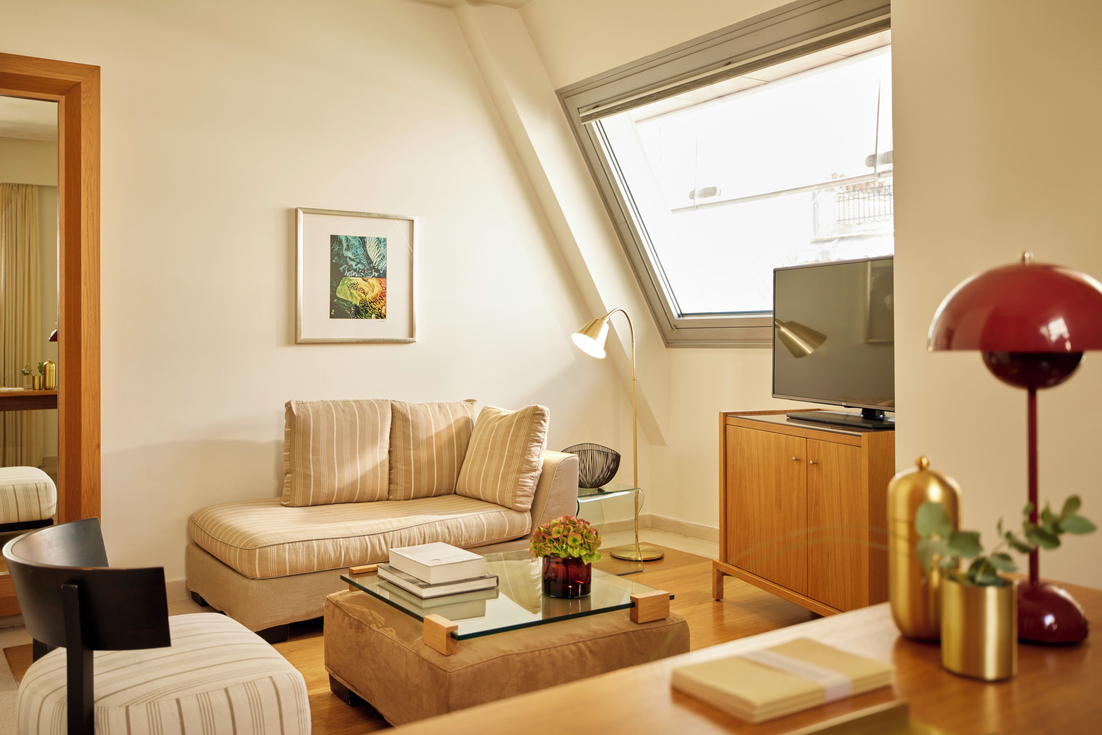 Ein modernes Wohnzimmer mit einer Couch, einem Couchtisch, einer TV-Konsole und einem großen Fenster.