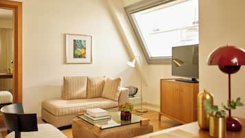 Ein modernes Wohnzimmer mit einer Couch, einem Couchtisch, einer TV-Konsole und einem großen Fenster.
