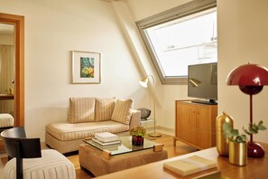 Una sala moderna con sofá, mesa de centro, mueble para televisión y un ventanal grande.