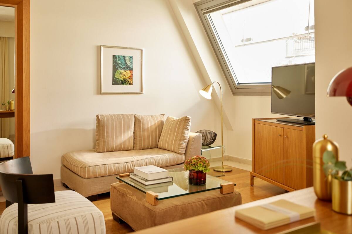 Een moderne woonkamer met een bank, een glazen salontafel, een televisie en een boekenkast.