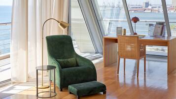 A modern room with a green armchair, a wooden desk, and a view of a bridge and water.