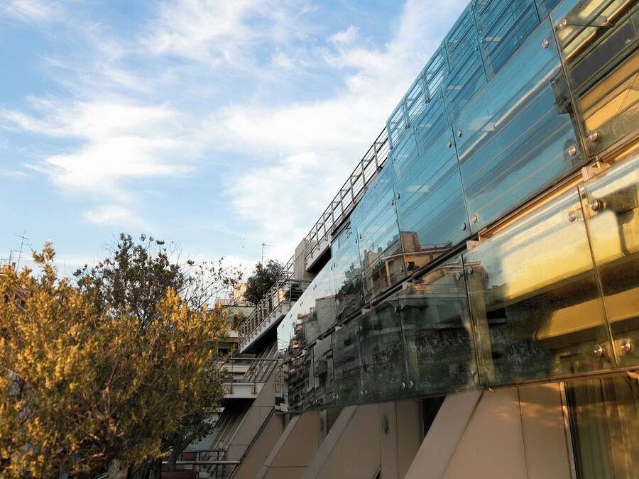 Een modern gebouw met een glazen gevel en een trap die naar een hoger gelegen verdieping leidt.