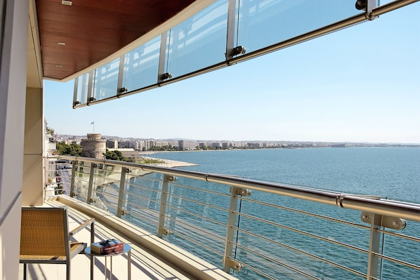 A balcony with a view of a body of water, a distant castle, and a cityscape.