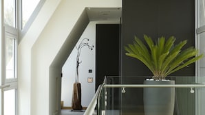 Een modern interieur met glazen balustrade, een grote potplant en een houten vloer.