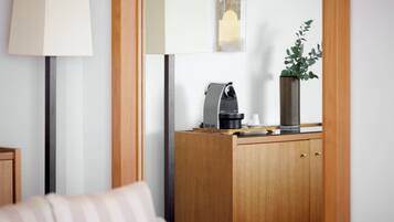 Una sala moderna con un aparador de madera, una cafetera, una taza y un florero con una planta.