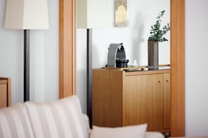 A modern living room with a wooden cabinet, a coffee machine, a cup, and a vase with a plant. - Daios Luxury Living (Thessaloniki)