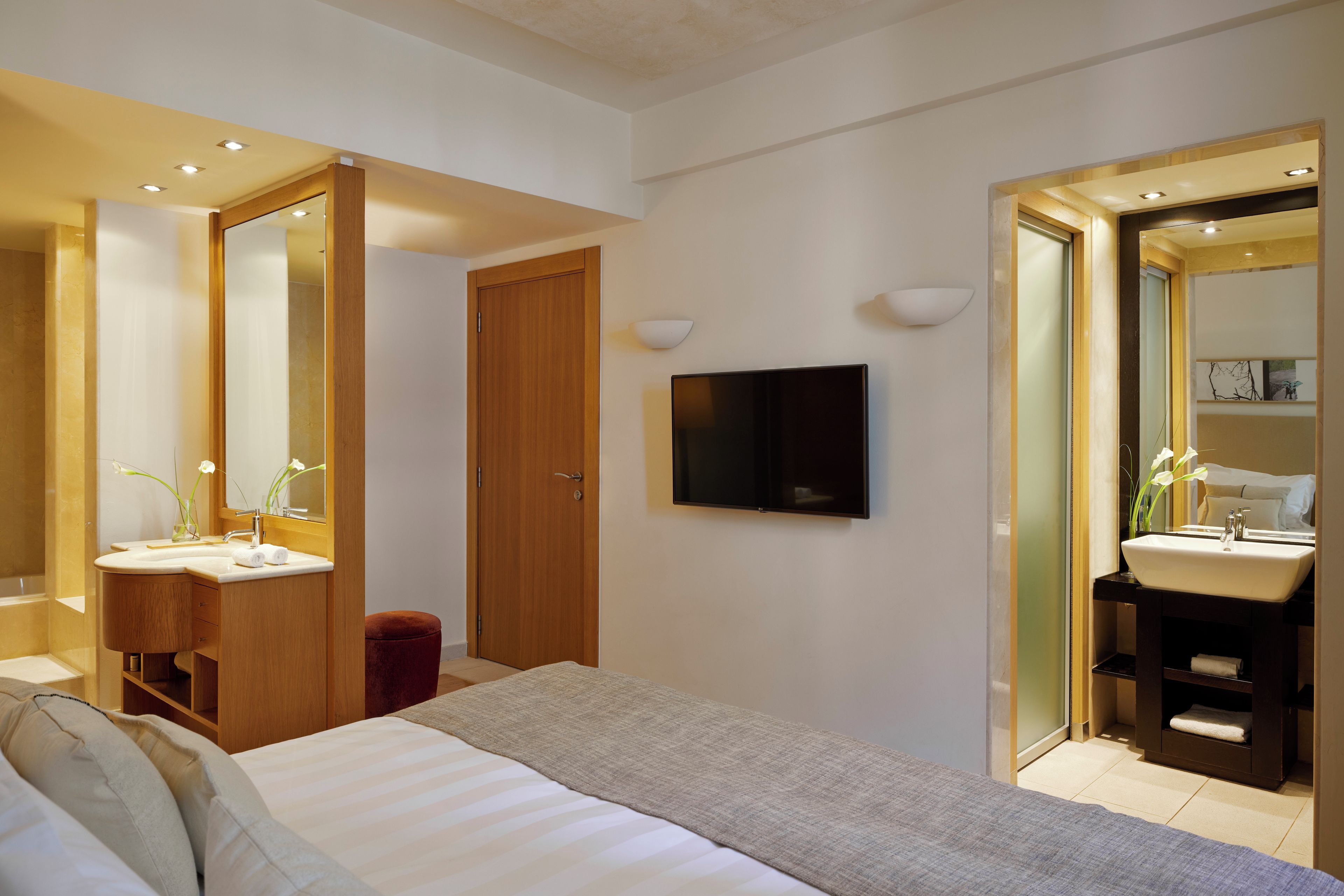 A modern bedroom with a bed, two bedside tables, a TV, and a large mirror.