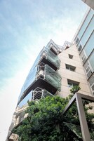 Un edificio de varios pisos con fachada de vidrio y una serie de balcones.