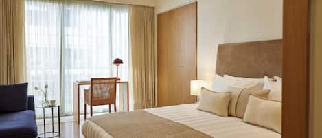 A hotel room with a bed, a desk, a chair, and a sofa.