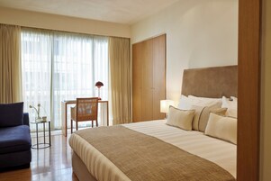 Una habitación de hotel con cama, escritorio, silla y sofá.