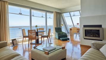 Amplia sala de estar con un ventanal con vistas al mar, un sofá cómodo, una mesa de centro de vidrio y una chimenea.