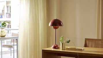 A wooden table with a red floor lamp, a potted plant, and a book.