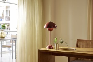 Una mesa de madera con una lámpara de pie roja, una planta en maceta y un libro.