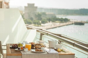 A breakfast table with various food items and a view of a river and buildings in the background.
