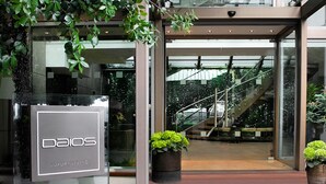 Een moderne gevel met glas, een bord met de tekst 'DAIOS LUXURY LIVING' en een trap die naar een hoger gelegen deel leidt.