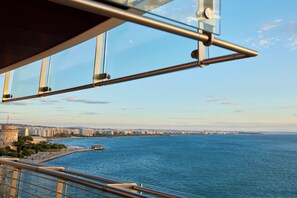 Un paisaje urbano costero con una vista despejada del mar, un puente y una torre histórica.