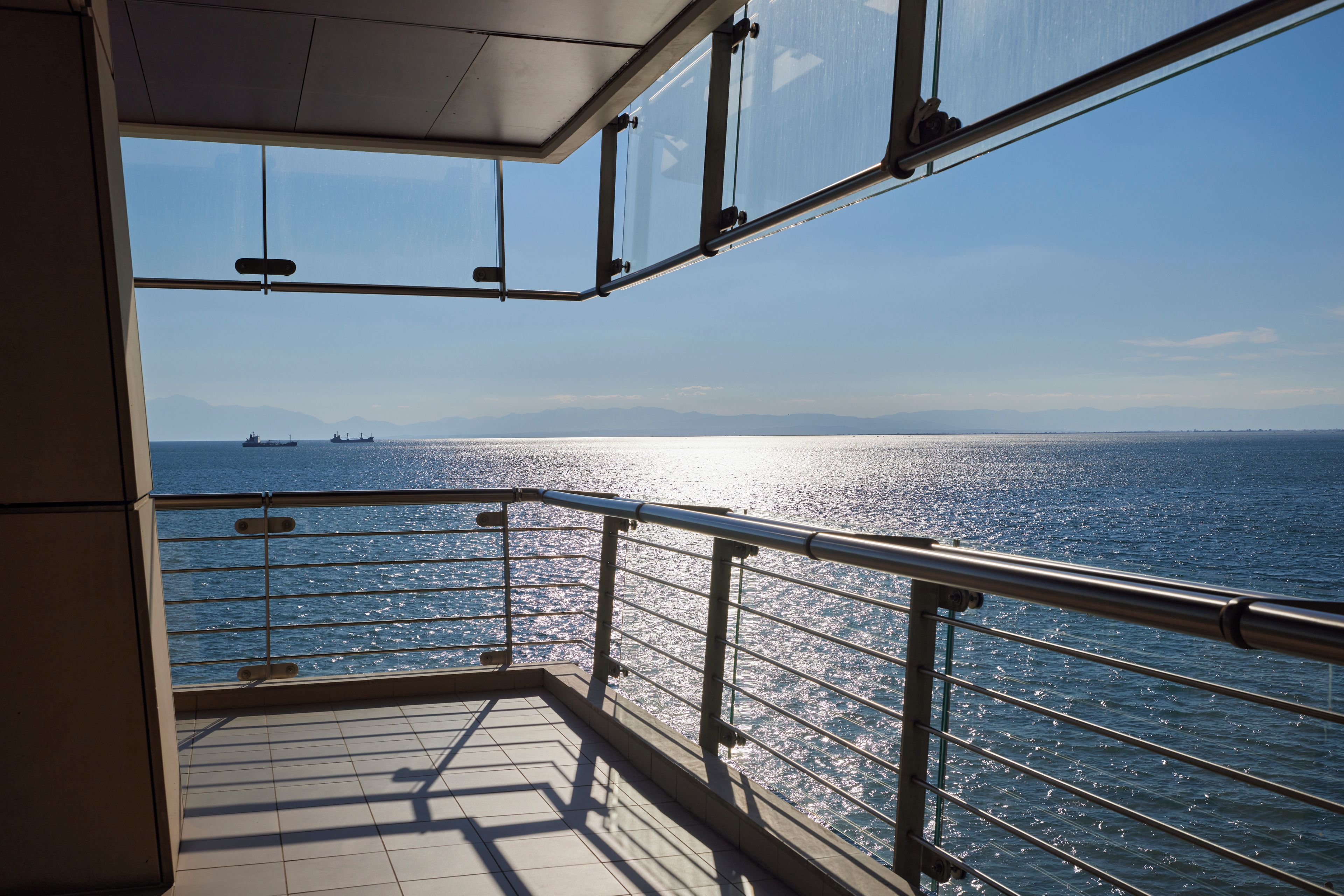 Un balcón con vista al mar y barcos a lo lejos.