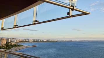 Un paisaje costero urbano con vista despejada al mar, una estructura imponente que recuerda a un castillo y un edificio moderno con fachada de vidrio.