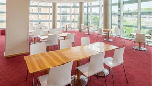 A spacious conference room with large windows, white chairs, and wooden tables. - Travelodge Windsor Central (Windsor)