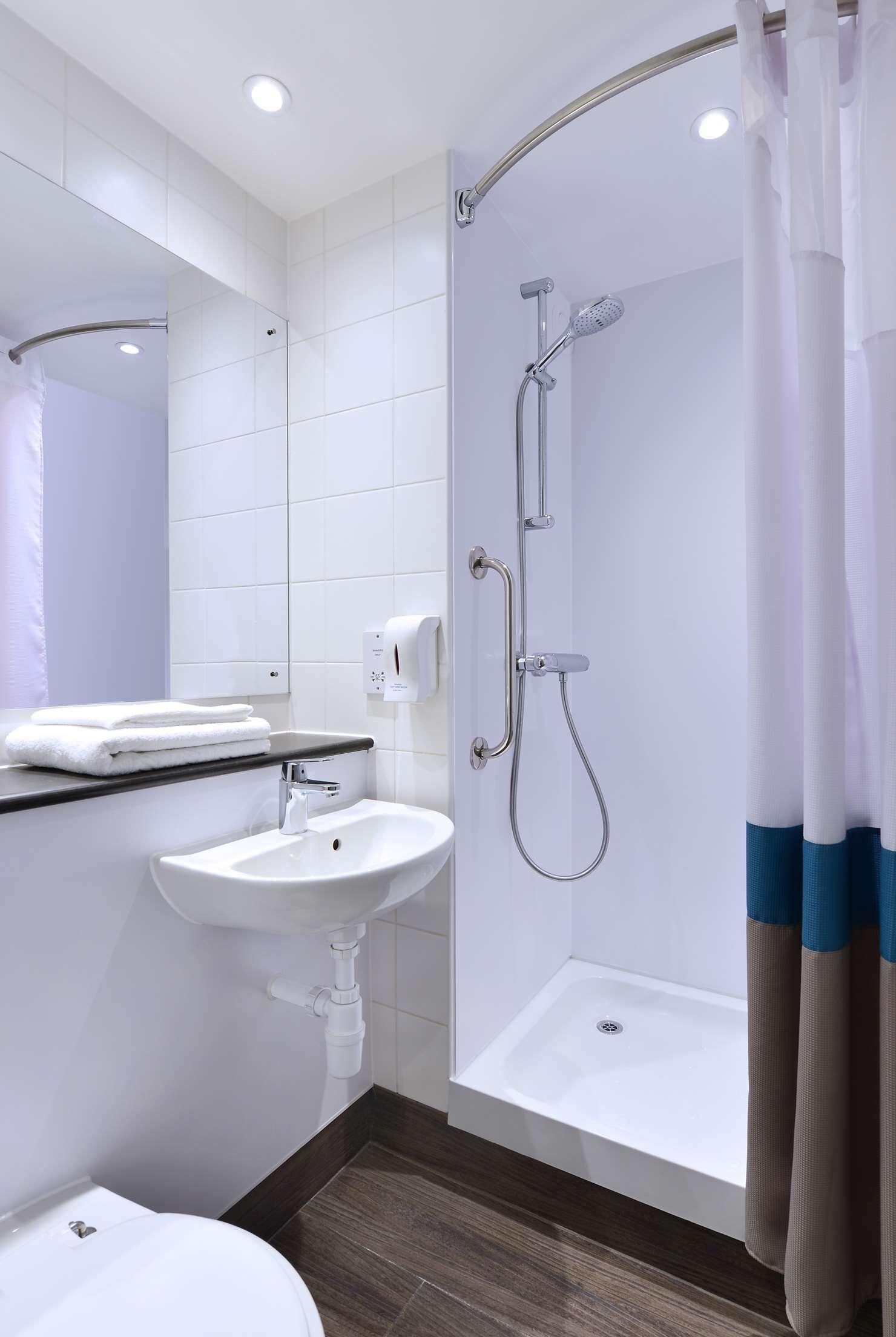 A modern bathroom with a shower, sink, and toilet.